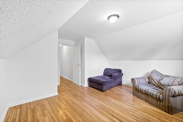 sitting room featuring a textured ceiling, baseboards, lofted ceiling, and light wood-type flooring