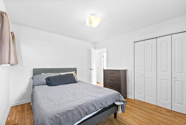 bedroom featuring light wood-type flooring, a closet, and baseboards