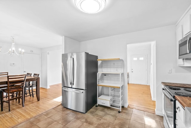 kitchen featuring an inviting chandelier, light tile patterned floors, white cabinetry, and stainless steel appliances