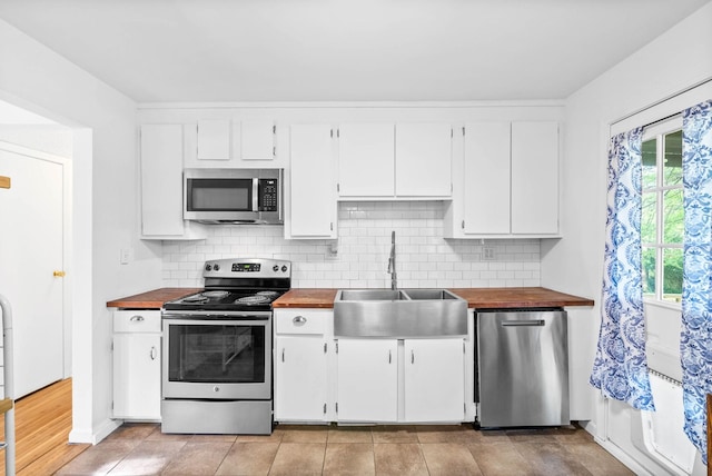 kitchen with stainless steel appliances, butcher block countertops, decorative backsplash, and a sink