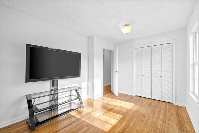 bedroom with baseboards, a textured ceiling, a closet, and wood-type flooring