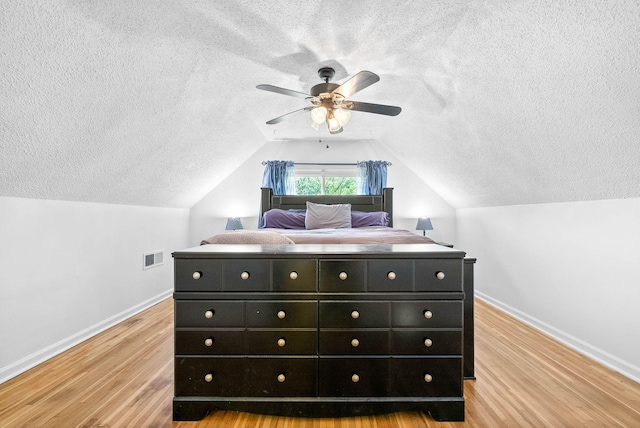 bedroom with a textured ceiling, visible vents, light wood-style flooring, and baseboards