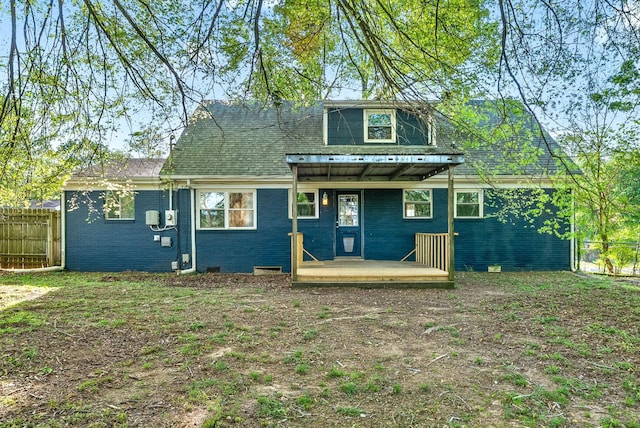 rear view of house with brick siding, crawl space, and fence