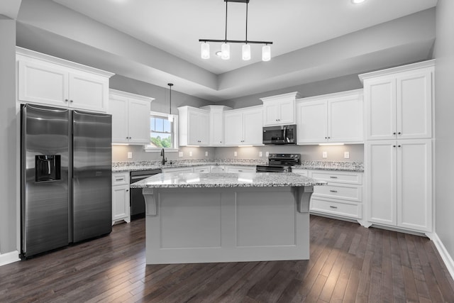 kitchen with dark wood-style floors, a kitchen island, appliances with stainless steel finishes, and white cabinetry