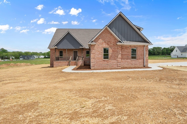 view of front of house with roof with shingles, board and batten siding, and brick siding