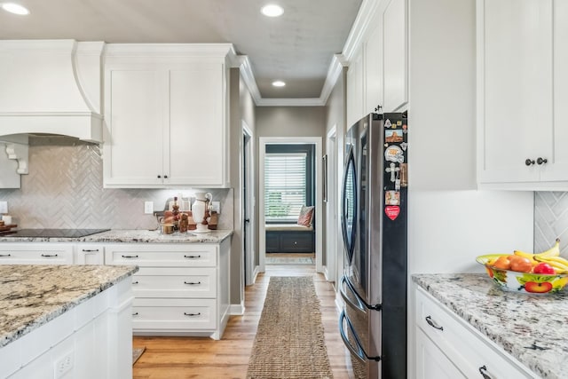 kitchen featuring custom range hood, freestanding refrigerator, and white cabinetry