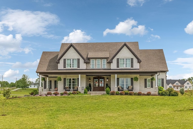 view of front of property featuring brick siding, french doors, covered porch, and a front yard