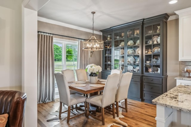 dining space with crown molding, recessed lighting, light wood-type flooring, and a chandelier