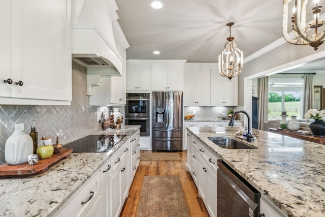 kitchen with light wood-type flooring, a sink, premium range hood, a chandelier, and stainless steel appliances