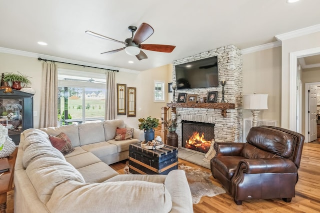 living area featuring ornamental molding, wood finished floors, a stone fireplace, recessed lighting, and a ceiling fan