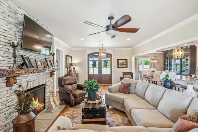 living area with crown molding, a fireplace, wood finished floors, ceiling fan with notable chandelier, and recessed lighting