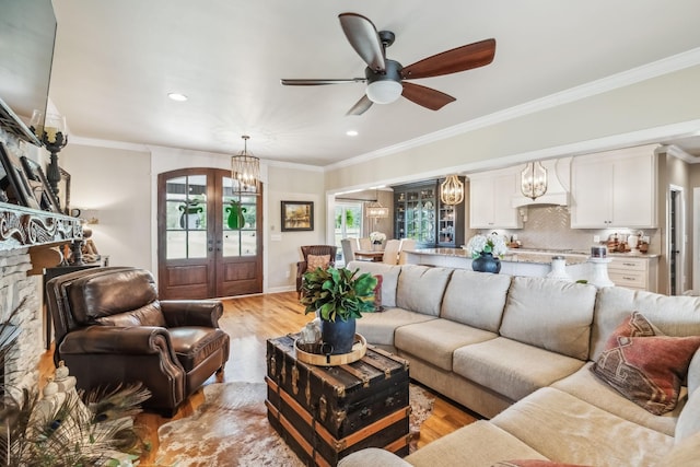 living area featuring ceiling fan with notable chandelier, french doors, light wood-type flooring, and a wealth of natural light