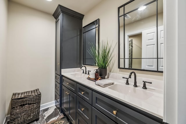 bathroom featuring double vanity, baseboards, a sink, and marble finish floor