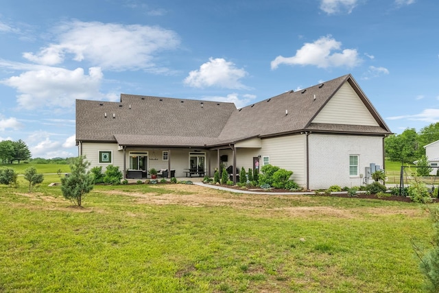 rear view of house featuring roof with shingles, a patio area, and a yard