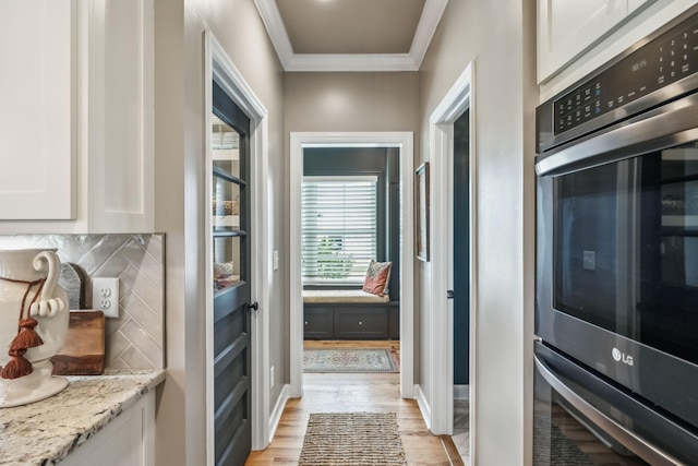 interior space with baseboards, ornamental molding, and light wood-style flooring