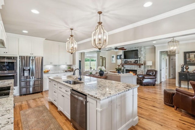 kitchen featuring a sink, appliances with stainless steel finishes, a fireplace, and open floor plan