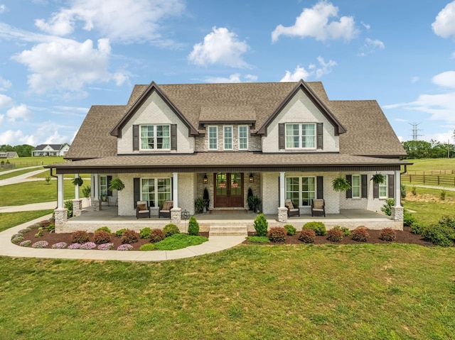 view of front facade with a porch, fence, a shingled roof, and a front yard