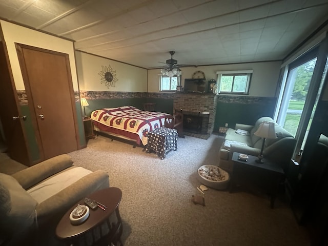 bedroom featuring a wainscoted wall, ceiling fan, carpet floors, and a fireplace