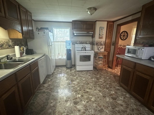 kitchen with stone finish floor, a sink, light countertops, under cabinet range hood, and white appliances