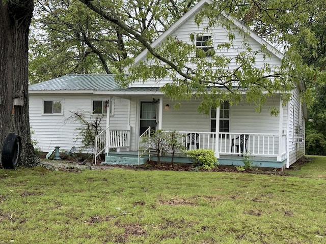 view of front facade featuring metal roof, a front lawn, and covered porch