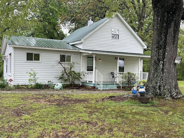 view of front of house with metal roof, a front lawn, and covered porch