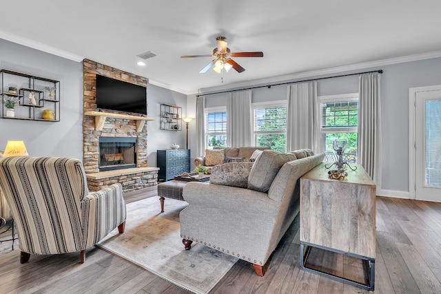 living room with wood finished floors, visible vents, a ceiling fan, and ornamental molding