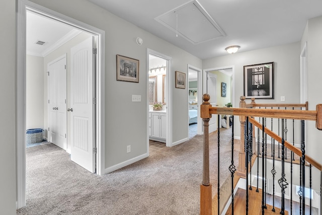 hallway with an upstairs landing, visible vents, baseboards, attic access, and light carpet