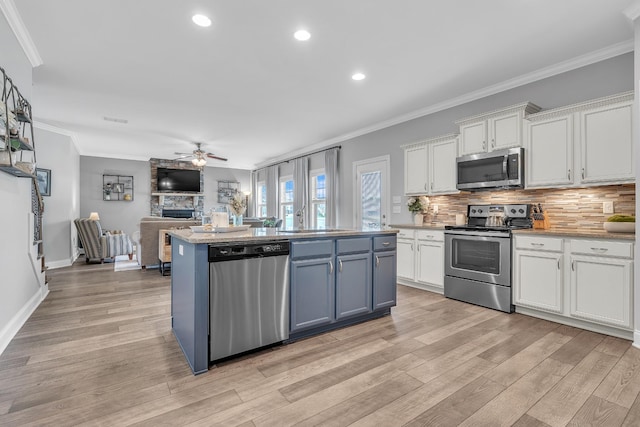 kitchen with a sink, white cabinets, appliances with stainless steel finishes, and open floor plan