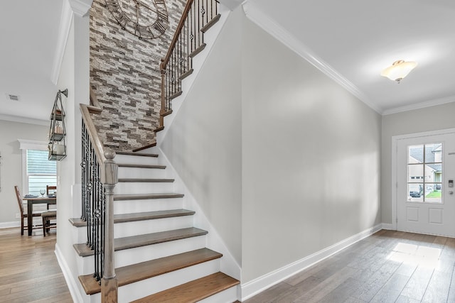foyer with visible vents, hardwood / wood-style floors, crown molding, and stairs