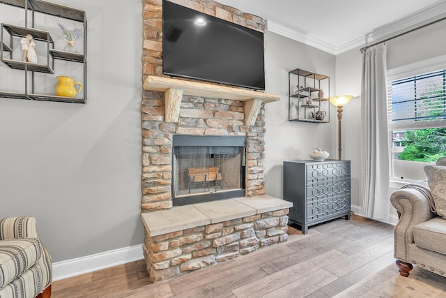 living room with baseboards, wood finished floors, a fireplace, and crown molding