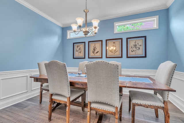 dining area with crown molding, a wainscoted wall, wood finished floors, and a chandelier