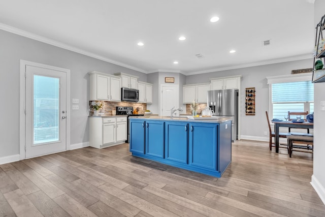 kitchen featuring appliances with stainless steel finishes, white cabinets, light wood finished floors, and a sink