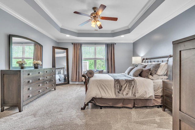 bedroom featuring ceiling fan, carpet floors, crown molding, and a tray ceiling