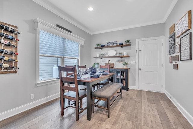 dining room with ornamental molding, light wood finished floors, and baseboards