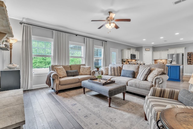 living area with light wood-type flooring, a ceiling fan, ornamental molding, and recessed lighting
