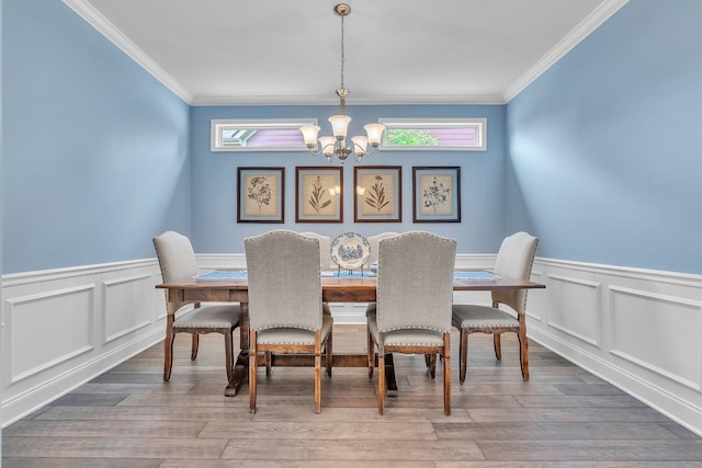 dining area featuring a chandelier, plenty of natural light, crown molding, and wainscoting
