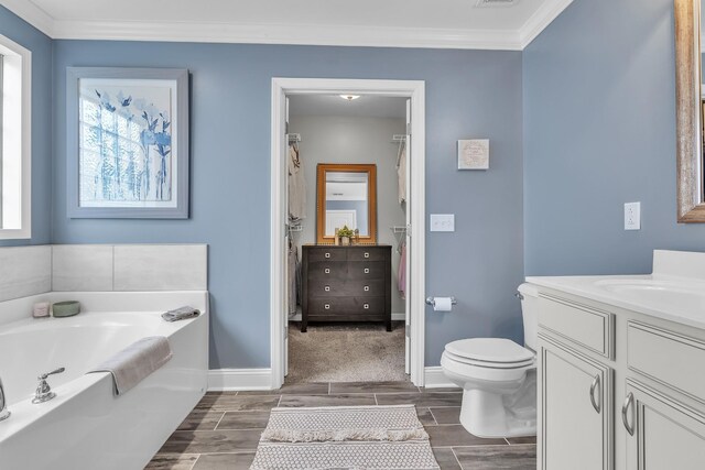 bathroom featuring wood tiled floor, toilet, ornamental molding, a garden tub, and vanity