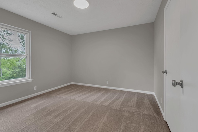 carpeted spare room featuring visible vents and baseboards