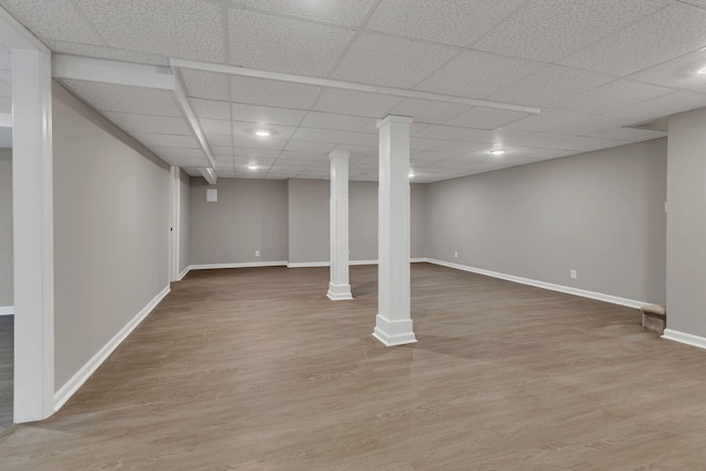 finished below grade area featuring wood finished floors, a paneled ceiling, and baseboards