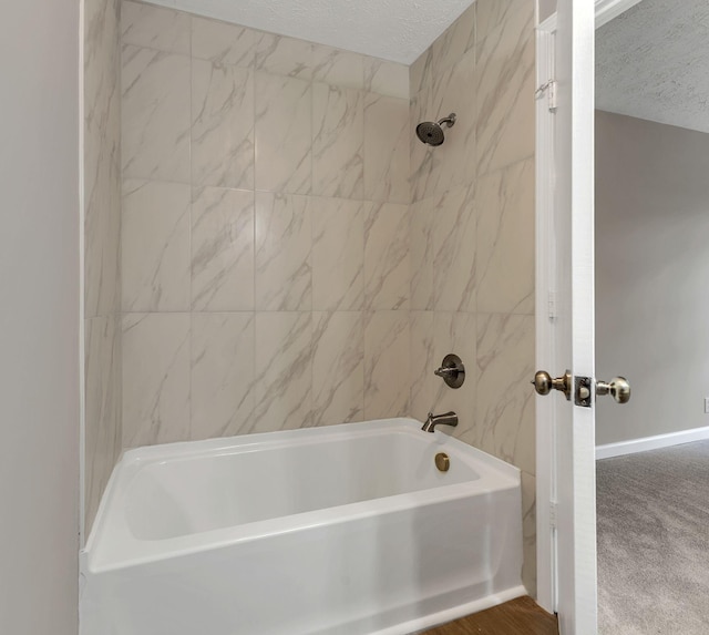 full bathroom with a textured ceiling and bathing tub / shower combination
