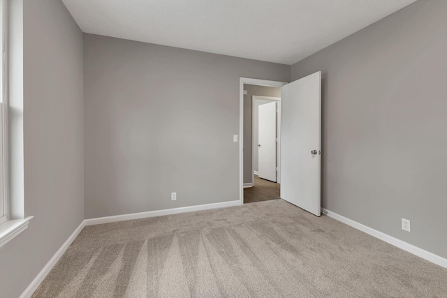 carpeted empty room featuring baseboards