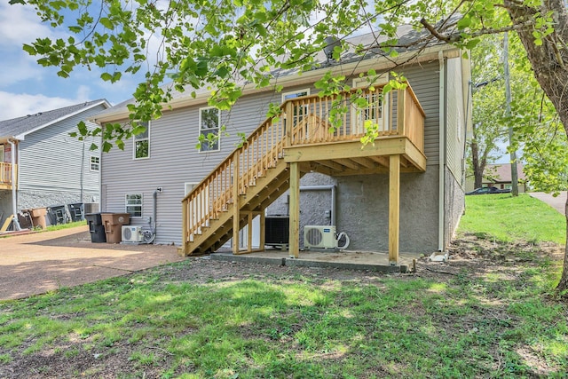 back of property with a deck, stairway, a yard, and ac unit