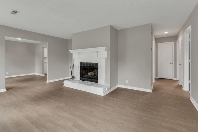 unfurnished living room featuring a fireplace, wood finished floors, visible vents, and baseboards