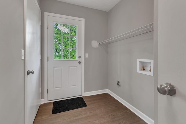 clothes washing area with dark wood-style floors, laundry area, hookup for a washing machine, electric dryer hookup, and baseboards