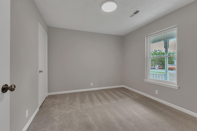 spare room featuring a textured ceiling, visible vents, carpet, and baseboards