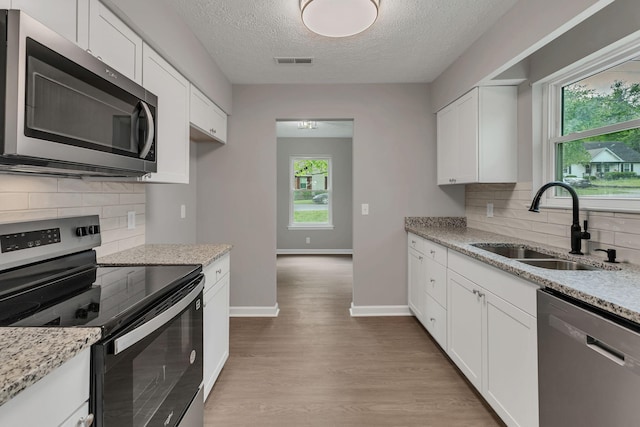 kitchen featuring decorative backsplash, a sink, stainless steel appliances, and visible vents