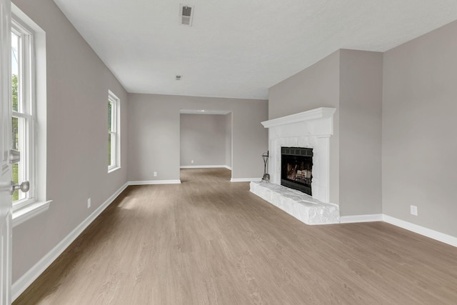 unfurnished living room with a brick fireplace, wood finished floors, and baseboards