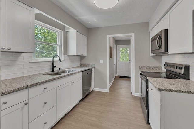 kitchen featuring a sink, white cabinetry, stainless steel appliances, and light wood-type flooring