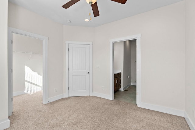 unfurnished bedroom featuring carpet flooring, connected bathroom, a closet, a ceiling fan, and baseboards