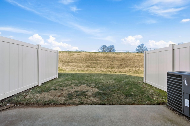 view of yard with central AC and fence